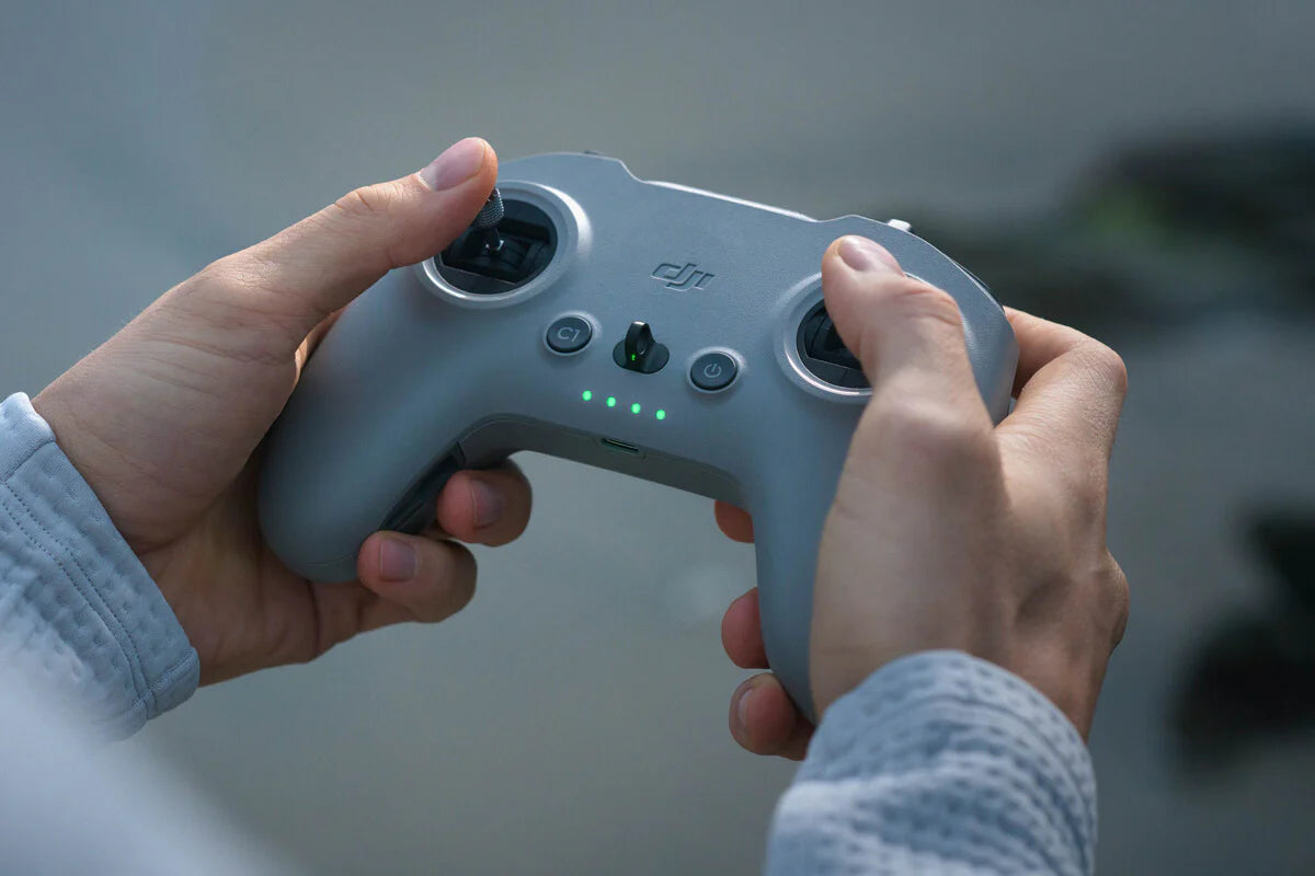 User holding the DJI FPV Remote Controller 3 with responsive controls and battery indicator.